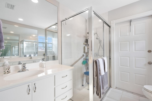 bathroom with a shower with door, vanity, tile patterned floors, and toilet