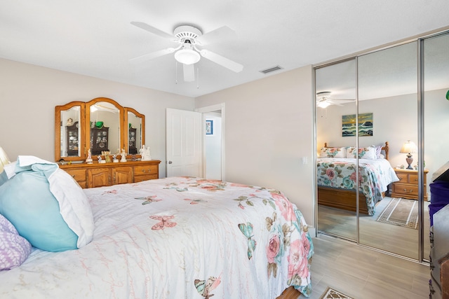 bedroom with a closet, light hardwood / wood-style floors, and ceiling fan