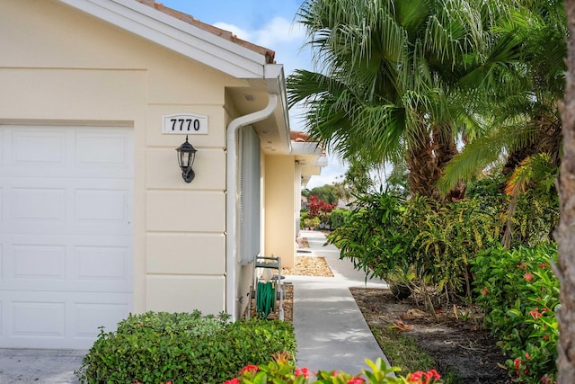 7770 SE Spicewood Cir, Hobe Sound, FL 33455 - view of exterior entry featuring an attached garage and stucco siding
