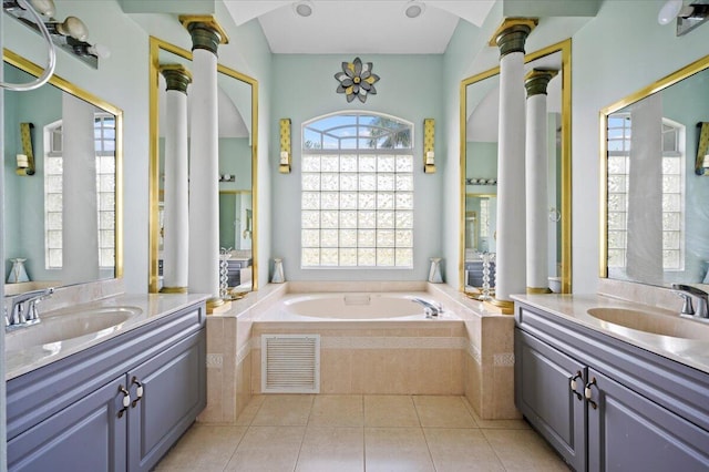 bathroom featuring tile patterned floors, vanity, ornate columns, and tiled tub