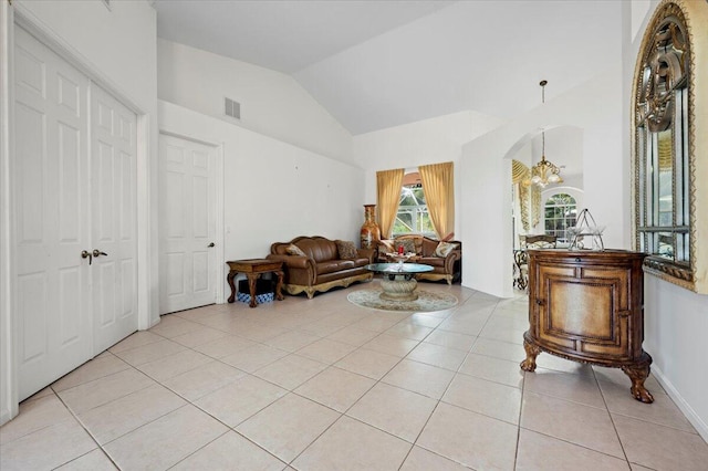 tiled living room with vaulted ceiling and a notable chandelier