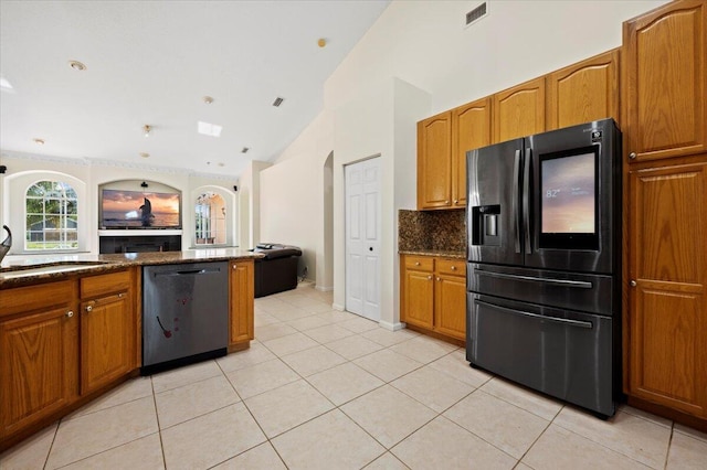 kitchen with backsplash, stainless steel appliances, vaulted ceiling, light tile patterned floors, and dark stone countertops