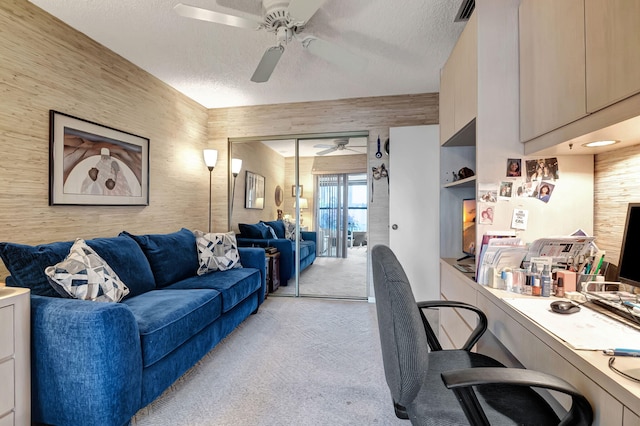 carpeted home office with ceiling fan and a textured ceiling