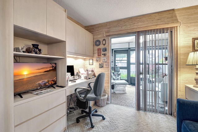 carpeted office space with wooden walls and a textured ceiling