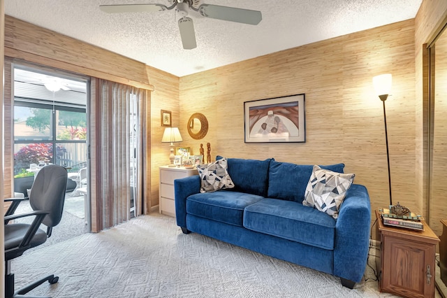 home office featuring ceiling fan, wooden walls, light carpet, and a textured ceiling