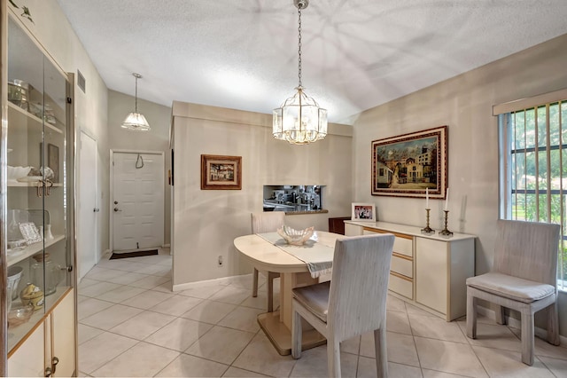 dining space featuring a notable chandelier, a textured ceiling, and light tile patterned floors