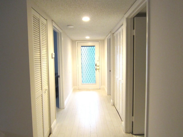 corridor featuring a textured ceiling and light hardwood / wood-style flooring