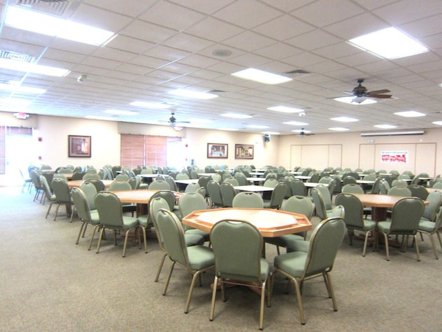 carpeted dining space with ceiling fan and a paneled ceiling