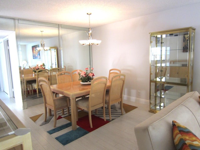 dining space with light hardwood / wood-style flooring, a textured ceiling, and a notable chandelier