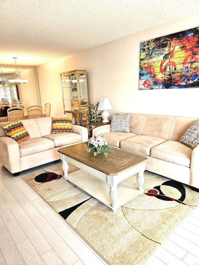 living room featuring an inviting chandelier, light hardwood / wood-style floors, and a textured ceiling