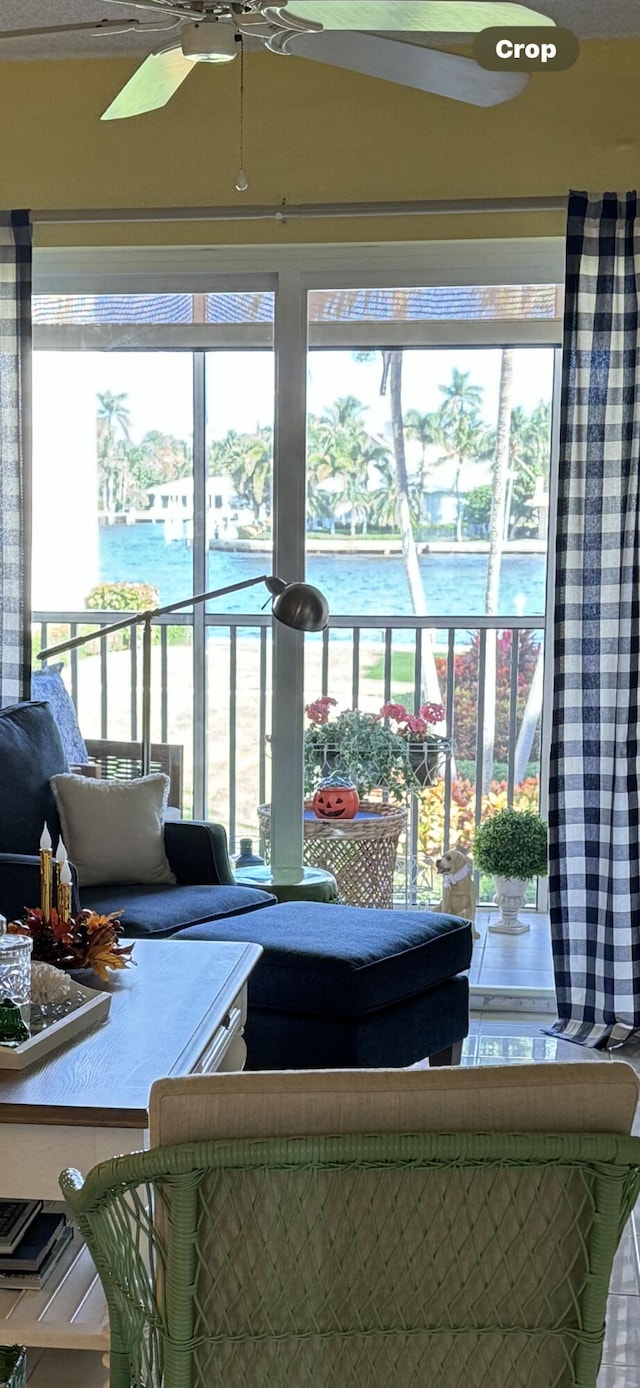 living room featuring ceiling fan, a water view, and a healthy amount of sunlight