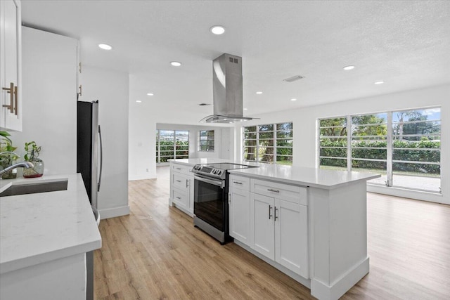 kitchen featuring sink, light wood-type flooring, island range hood, white cabinetry, and stainless steel appliances