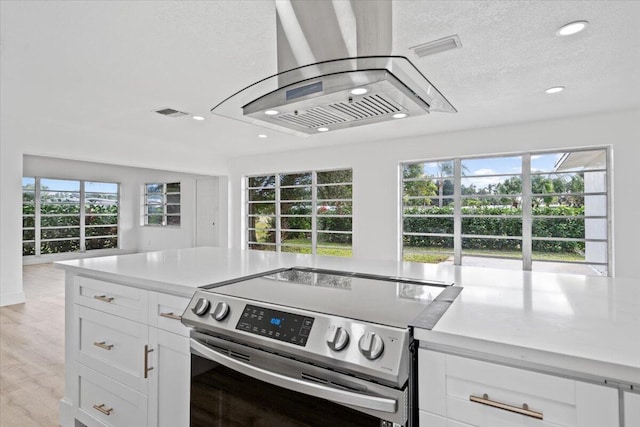 kitchen featuring a healthy amount of sunlight, white cabinetry, and stainless steel range with electric cooktop