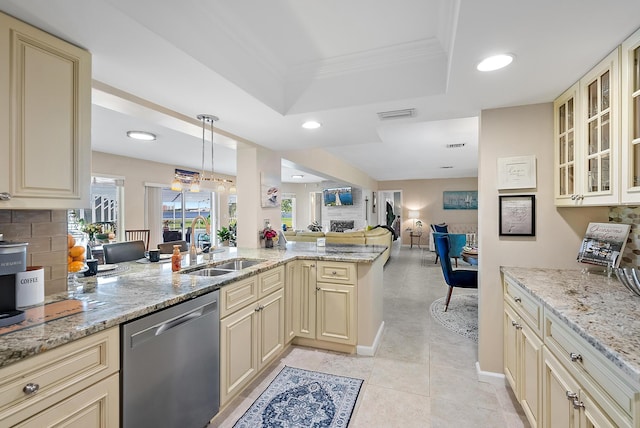 kitchen featuring sink, stainless steel dishwasher, backsplash, a tray ceiling, and cream cabinetry