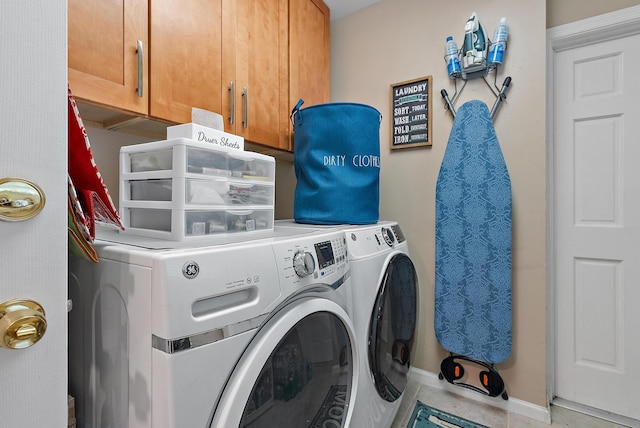 clothes washing area featuring cabinets and washing machine and clothes dryer