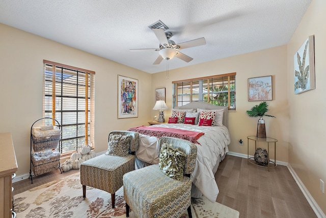 bedroom with hardwood / wood-style floors, a textured ceiling, and ceiling fan