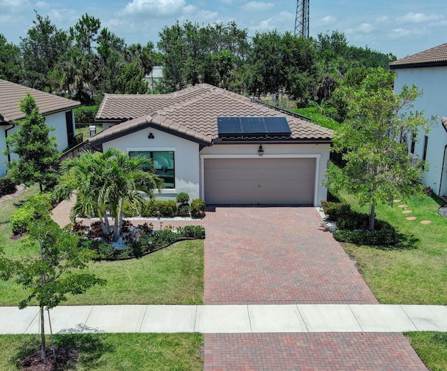 view of front facade featuring a garage, solar panels, and a front yard