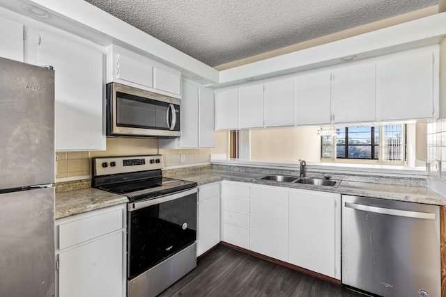 kitchen with stainless steel appliances, dark wood-type flooring, sink, a textured ceiling, and white cabinetry