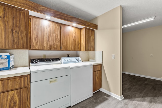 washroom featuring a textured ceiling, separate washer and dryer, dark wood-type flooring, and cabinets