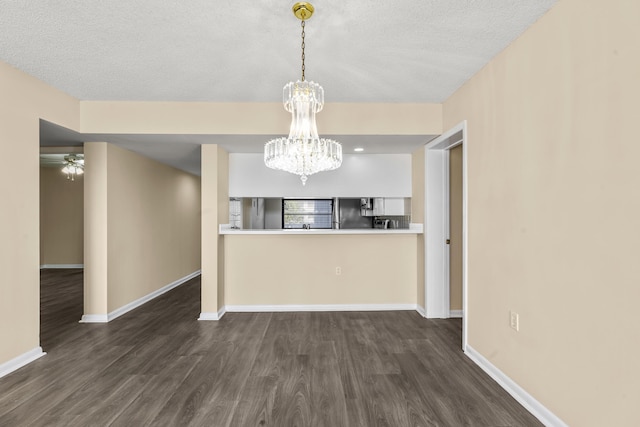 unfurnished dining area with dark wood-type flooring, a chandelier, and a textured ceiling