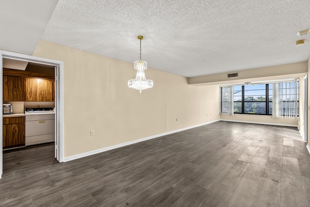 interior space with a textured ceiling, dark hardwood / wood-style floors, a chandelier, and washer / dryer