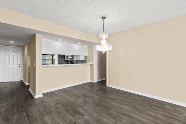 interior space with kitchen peninsula, a textured ceiling, extractor fan, dark hardwood / wood-style floors, and pendant lighting