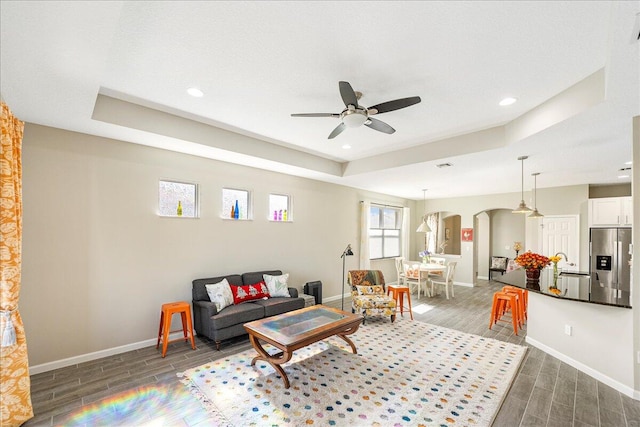 living room with ceiling fan, dark hardwood / wood-style floors, and a raised ceiling