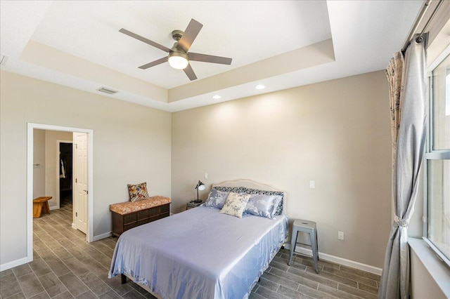 bedroom featuring dark hardwood / wood-style flooring, ceiling fan, and a tray ceiling