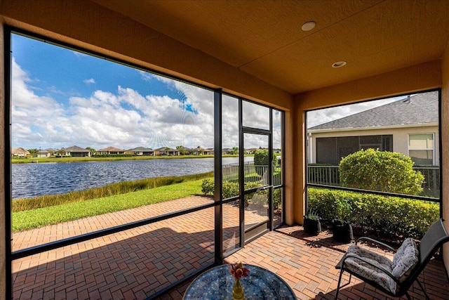 sunroom featuring a water view