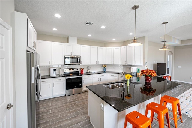 kitchen with kitchen peninsula, a kitchen bar, pendant lighting, and appliances with stainless steel finishes