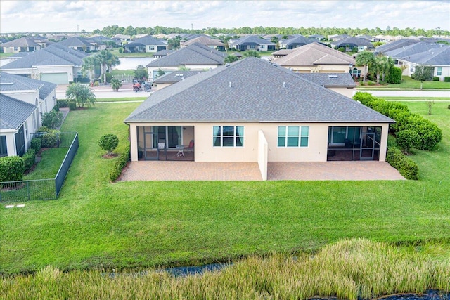 rear view of house featuring a lawn, a sunroom, a water view, and a patio area