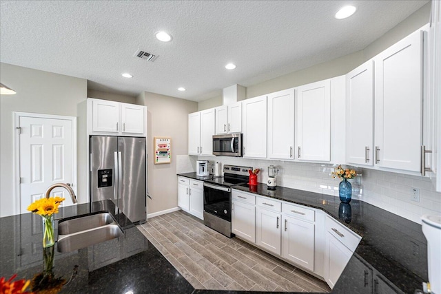 kitchen with white cabinets, dark stone counters, and appliances with stainless steel finishes