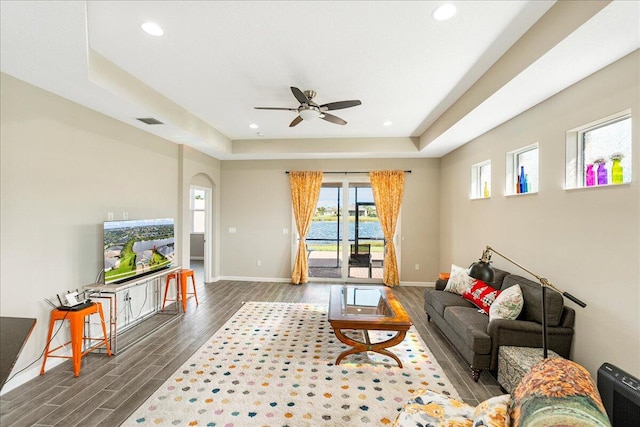 living room featuring ceiling fan, dark hardwood / wood-style floors, and a raised ceiling