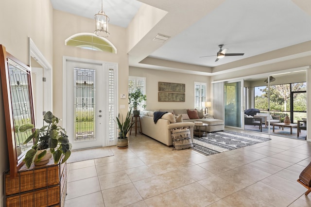 entrance foyer with light tile patterned floors, ceiling fan, a raised ceiling, and visible vents