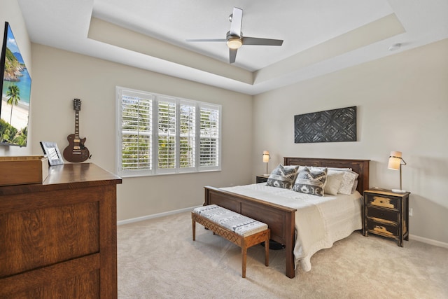 bedroom featuring ceiling fan, baseboards, a raised ceiling, and light colored carpet