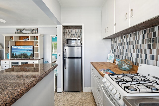 kitchen featuring backsplash, dark stone counters, crown molding, appliances with stainless steel finishes, and white cabinetry