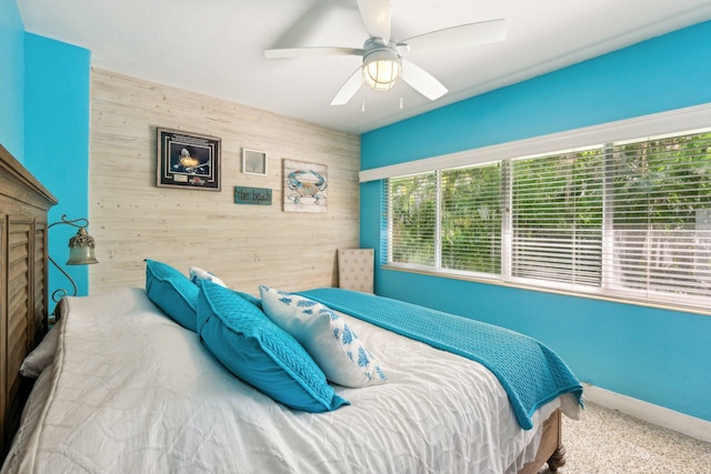 carpeted bedroom with ceiling fan and wooden walls