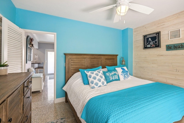 carpeted bedroom featuring ceiling fan and wood walls