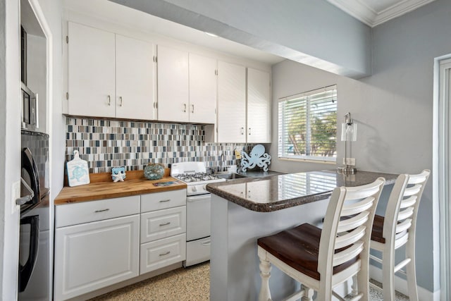 1006 Casuarina Rd Unit 11, Delray Beach, FL 33483 - kitchen featuring white range with gas cooktop, crown molding, backsplash, white cabinetry, and a breakfast bar area