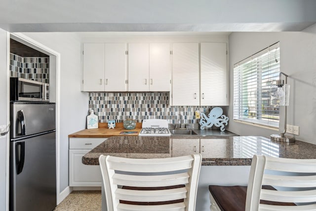 1006 Casuarina Rd Unit 11, Delray Beach, FL 33483 - kitchen with stainless steel appliances, backsplash, white cabinets, and a sink