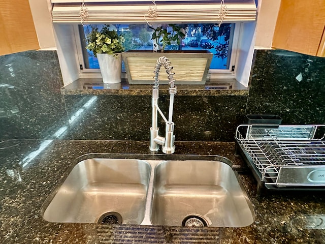 room details with dark stone countertops, sink, and tasteful backsplash