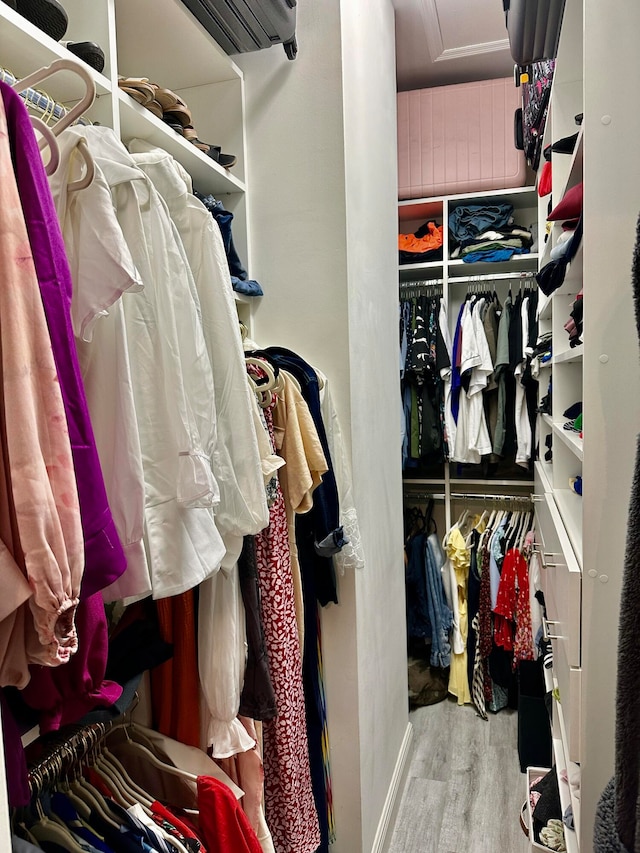 walk in closet featuring a wall mounted AC and light wood-type flooring