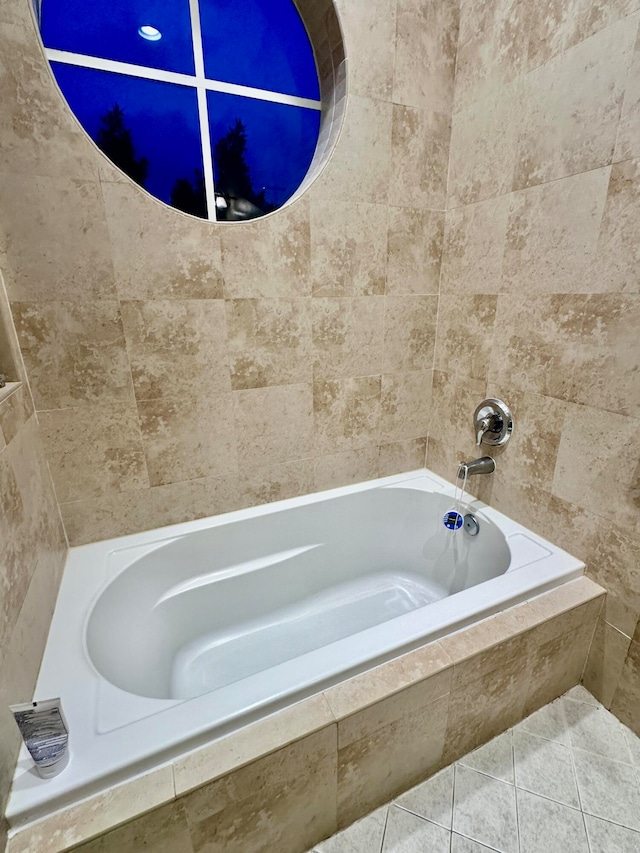 bathroom with tile patterned floors and a relaxing tiled tub