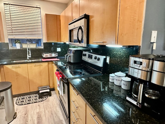 kitchen featuring sink, stainless steel appliances, backsplash, dark stone countertops, and light hardwood / wood-style floors