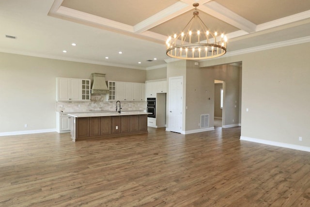 kitchen with decorative backsplash, custom exhaust hood, a center island with sink, white cabinets, and dark hardwood / wood-style floors