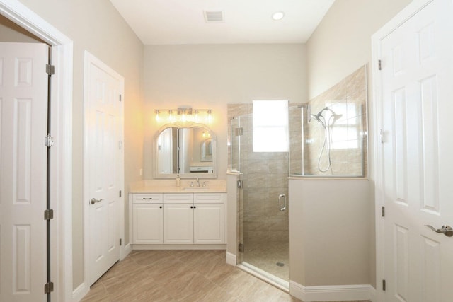 bathroom featuring a shower with door and vanity