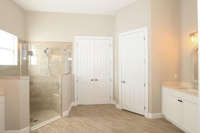 bathroom featuring a shower with door and vanity