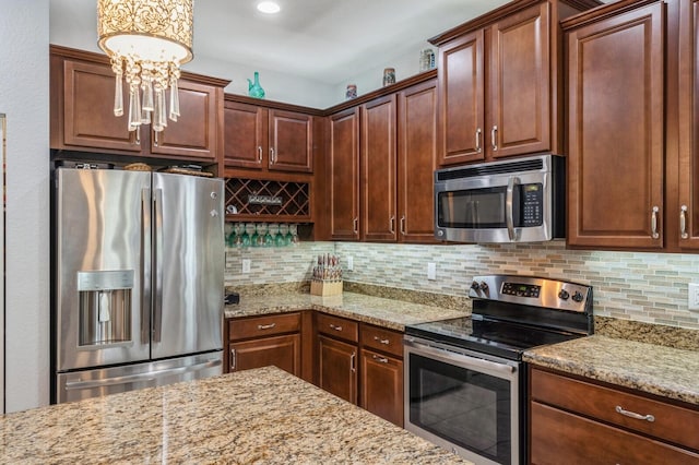 kitchen featuring stainless steel appliances, light stone counters, and backsplash