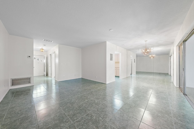 spare room featuring an inviting chandelier and a textured ceiling