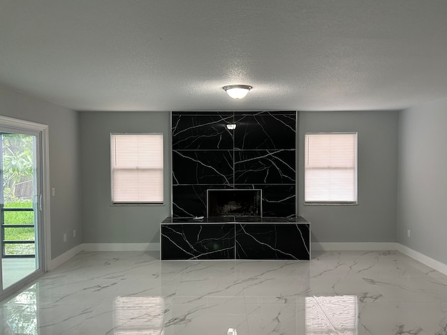 interior space with a tiled fireplace and a textured ceiling